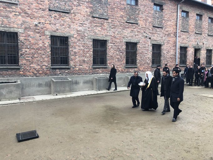 HE Dr. Mohammad Alissa lights a candle at the Wall of Executions in memory of all those killed there while visiting Auschwitz Museum with delegates from AJCGlobal