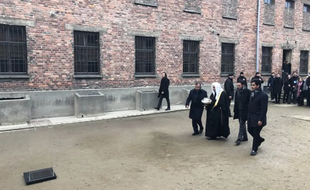 HE Dr. Mohammad Alissa lights a candle at the Wall of Executions in memory of all those killed there while visiting Auschwitz Museum with delegates from AJCGlobal